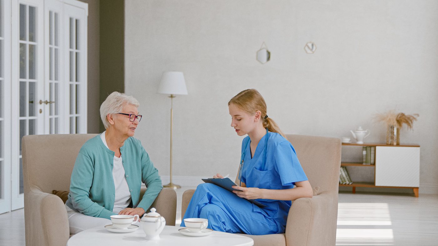 Older woman talking with a healthcare professional at home — guidance before choosing mobility equipment
